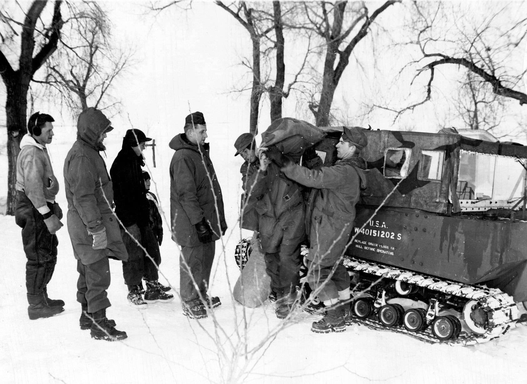 Soldiers unload sacks of coal from a weasel at the home of Mrs. Troy Howard near O'Neill. The grinning youngster is Joseph Howard. He has a reason to smile, Corp. Richard J. McDaniels is handing him a box of food. Published Feb. 4, 1949.